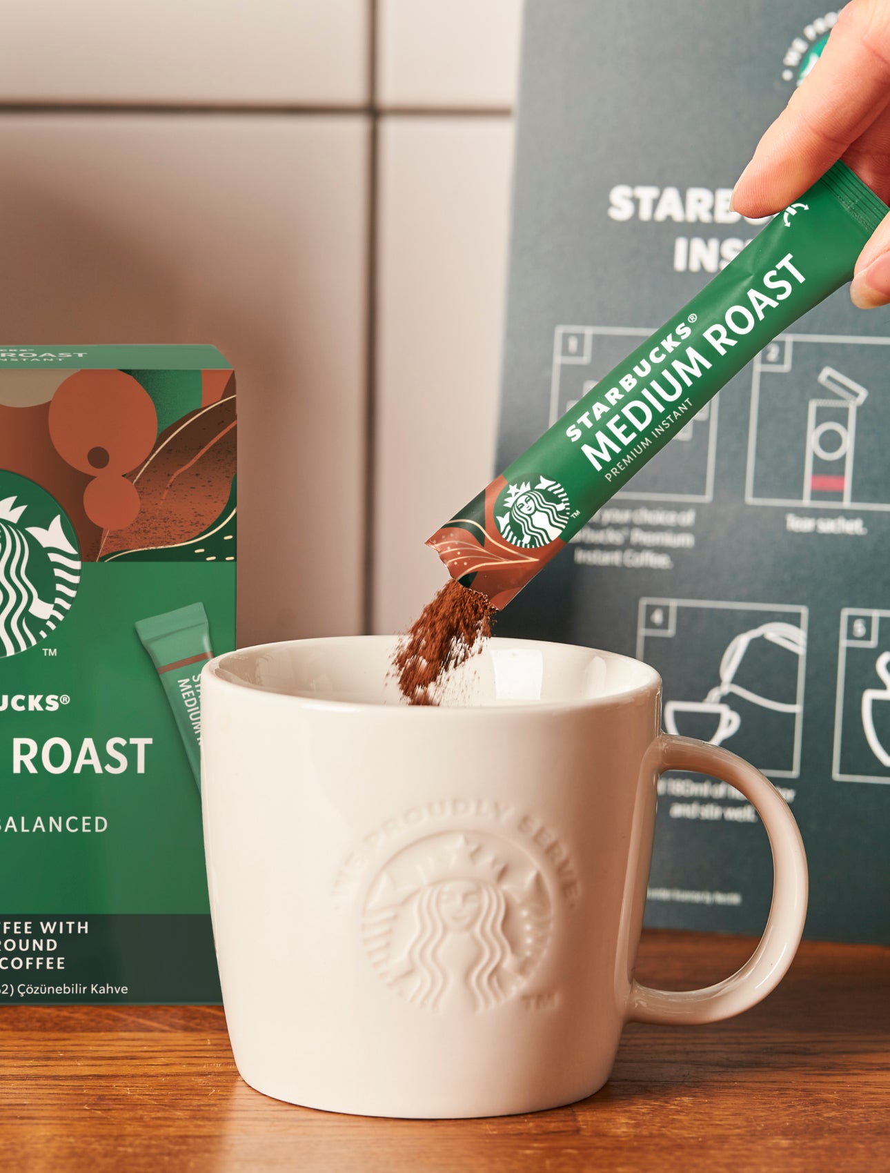 Et Starbucks Premium Instant Medium Roast-kaffebrev hældes i et We Proudly Serve Starbucks-keramikkrus 