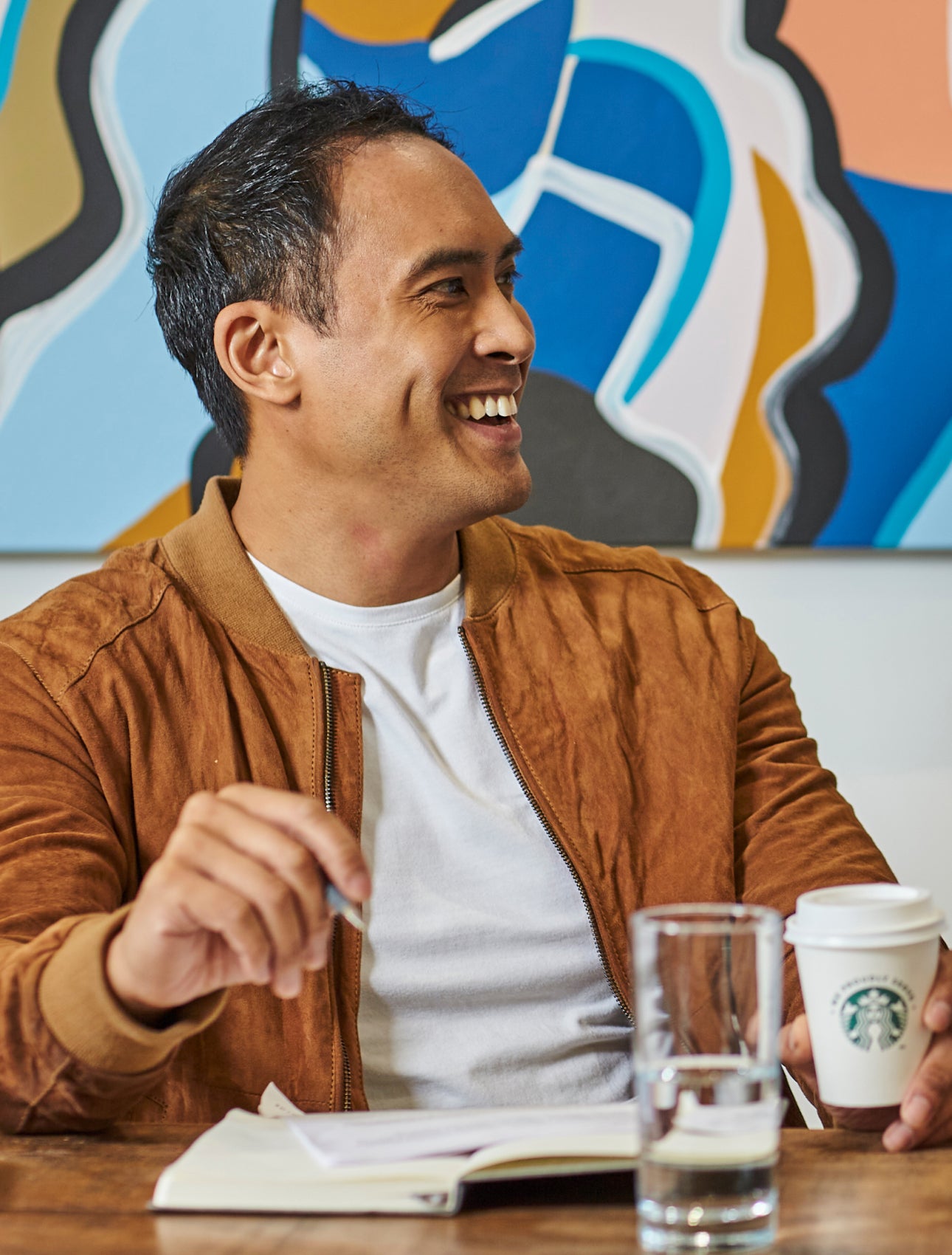 En gruppe mænd sidder ved et bord og nyder en kop We Proudly Serve Starbucks-kaffe 
