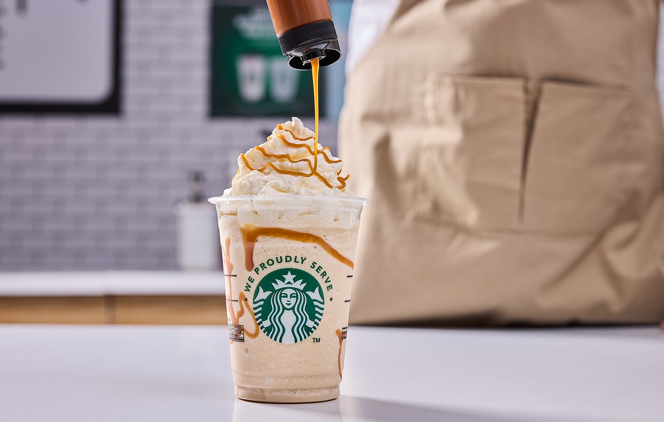 En Starbucks-blend toppet med flødeskum og en barista, der drysser karamel ovenpå 