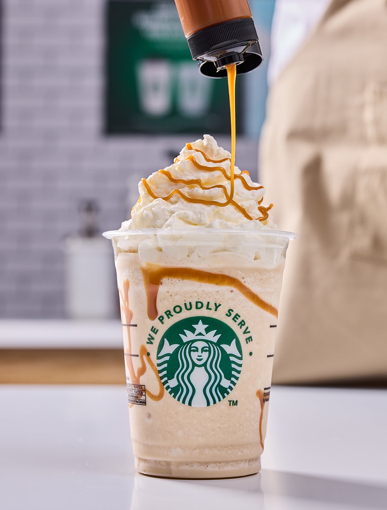 En Starbucks-blend toppet med flødeskum og en barista, der drysser karamel ovenpå 