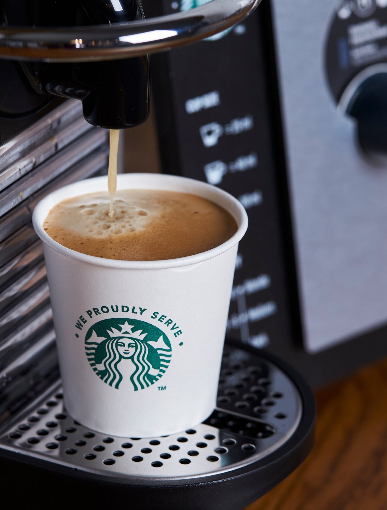 Et We Proudly Serve Starbucks-papbæger fyldes med friskbrygget kaffe fra en espressomaskine