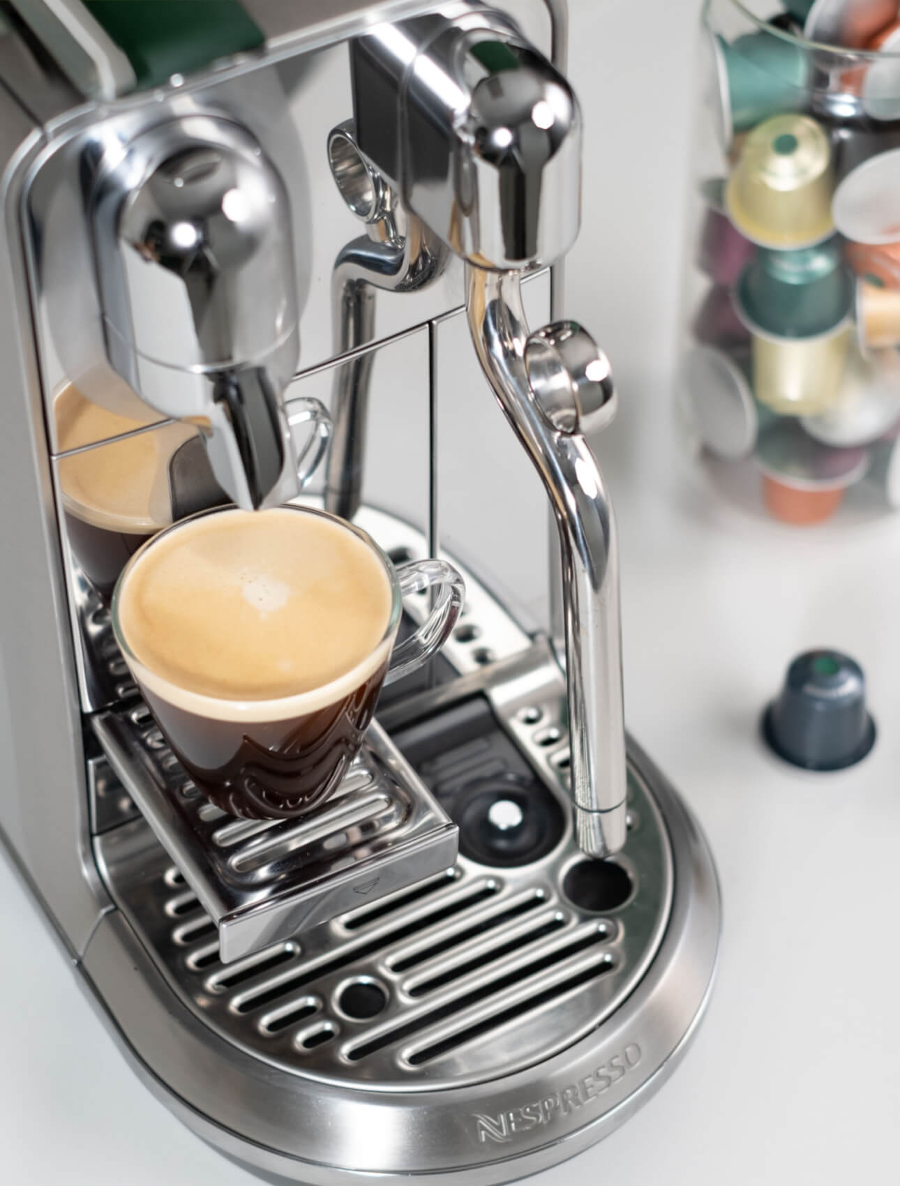 Nespresso-maskine med kaffe og We Proudly Serve Starbucks-kapsler i baggrunden