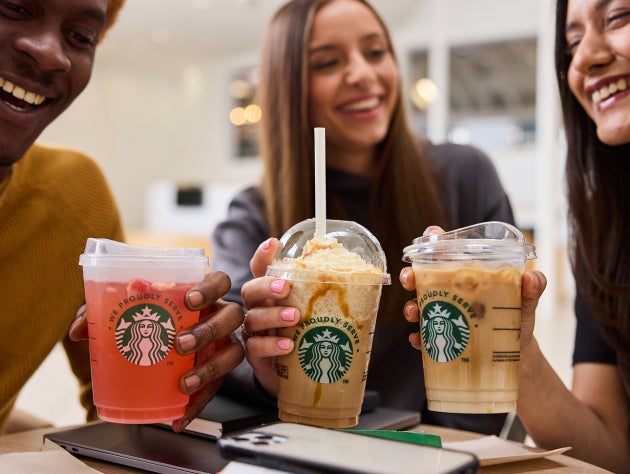 En gruppe venner holder tre iskolde Starbucks-drikke op i luften