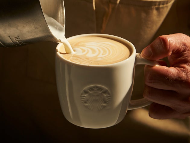 Person, der hælder mælk i et Starbucks-krus for at skabe latte art