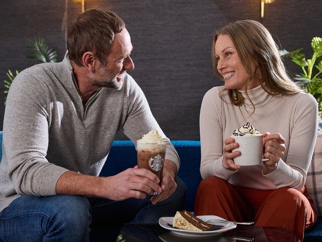 En mand og en kvinde sidder sammen og nyder varme og kolde Starbucks-drikke