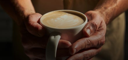 Et nærbillede af hænder, der holder et bæger med Starbucks-kaffe