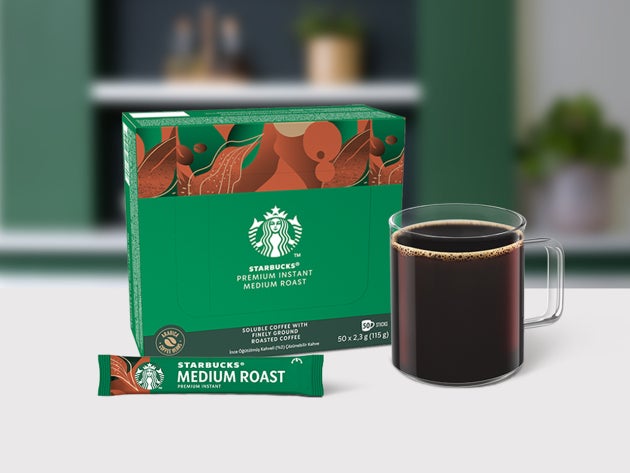 Starbucks® Premium Instant Medium Roast-kaffe i et glaskrus vist sammen med et brev og emballage
